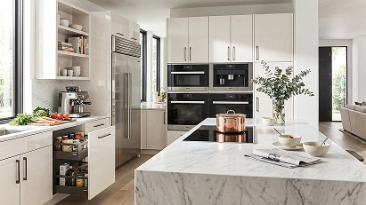 Modern slab kitchen cabinets in light tones with clean lines, integrated appliances and a peninsula.
