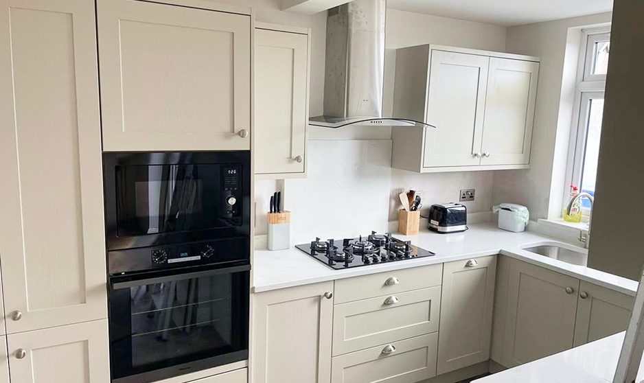 Painted Shaker U-shaped fitted kitchen in Mussel with quartz worktop, tall oven housing and window sink in Dublin.