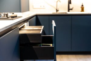 A corner kitchen setup with open drawers, showing a unified area between stovetop and sink. Perfect balance of function and form.