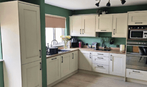 Cream shaker kitchen in Dublin with green walls and wood worktops.