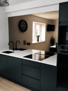 Handleless slab kitchen in Dublin with sink, hob, white worktop and dark green finish.