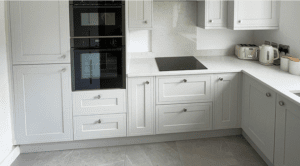 Light grey shaker kitchen with built-in ovens and quartz worktops in Sandycove Dublin