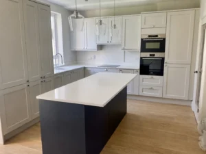 Modern shaker kitchen in Dublin with marine blue island, white cabinetry and integrated ovens.