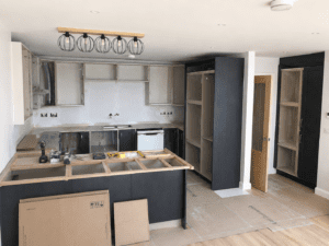 Indigo and grey Shaker kitchen installation in progress in Lucan, Dublin with U-shaped peninsula layout, partially fitted cabinets and worktop preparation