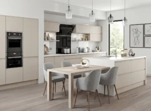 Modern cashmere kitchen renovation with island, dining table, integrated ovens and pendant lighting in a bright Irish home