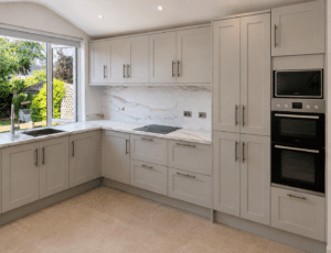 Light neutral Shaker kitchen in Malahide, Dublin with marble-effect laminate worktops, tall storage cabinets and integrated ovens.
