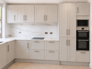 Linen Shaker kitchen renovation in Malahide, Dublin featuring integrated ovens, tall cabinets and a marble-effect quartz splashback.