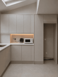 Right side of a modern U-shaped kitchen with sink appliance station under-cabinet lighting and tall utility niche