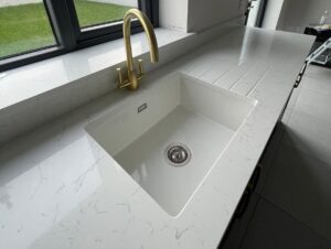 White quartz worktop with undermount ceramic sink and brushed brass tap in Killiney kitchen