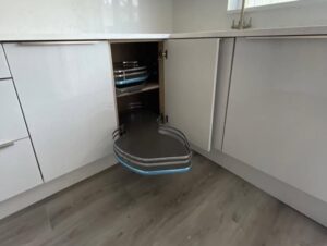 Corner pull-out storage in a white handleless kitchen in Malahide, Dublin