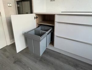 Hidden pull-out bin in a white high gloss handleless kitchen in Malahide, Dublin
