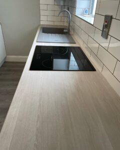 Sand Artisan Beech laminate worktop with black glass hob in Santry