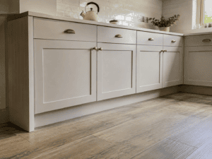 Cashmere slab kitchen with white worktops, brass handles and breakfast bar seating in an Irish home