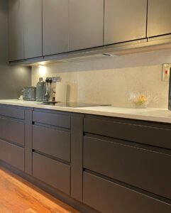 Graphite handleless cabinets with an induction hob and matching white quartz worktop and splashback in Rathfarnham, Dublin