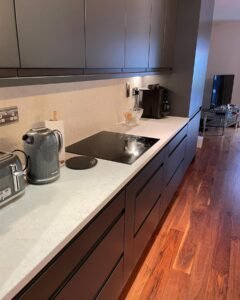 Induction hob with a white quartz worktop and matching splashback in a graphite handleless kitchen in Rathfarnham, Dublin