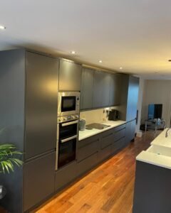 Graphite handleless kitchen with integrated ovens, an induction hob and white worktops in Rathfarnham, Dublin