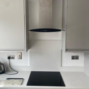 Four-zone black glass hob and curved glass extractor set into a light grey handleless kitchen worktop