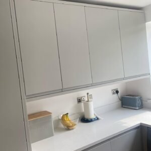 Full-height light grey handleless wall cabinets extending almost to the ceiling above an everyday worktop