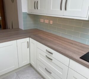 Light Tivoli laminate worktop meeting at an internal corner in a white shaker kitchen, with subway tile splashback
