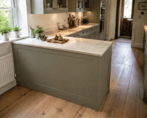 Small kitchen peninsula with a light stone-effect worktop in a sage green Shaker kitchen in an Irish home.