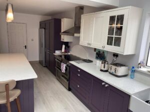 Central island and main cooking wall in a two-tone Shaker kitchen, showing the walkway between the island and the range cooker