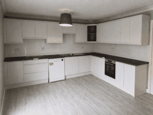 White Grey handleless L-shaped kitchen with dark worktops and an integrated oven in Lucan, Dublin