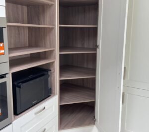 Open white shaker larder unit with adjustable wood-effect shelving in a Dundrum kitchen