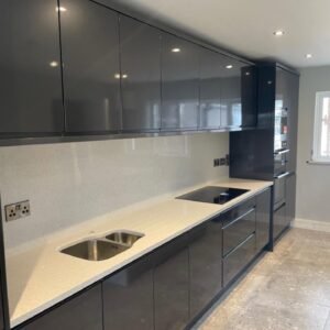 Sink, hob and appliance tower along the main wall of a gloss graphite handleless kitchen in Portmarnock, Dublin