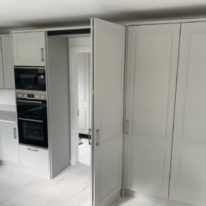 The same hidden door in a Castleknock kitchen, open, revealing the doorway to the adjoining space