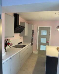 View along a light grey handleless kitchen in Sutton, Dublin, showing the cooking wall, island and appliance tower