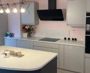 Light grey handleless kitchen with a graphite island in Sutton, Dublin, beneath a soft pink wall