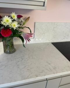 Close-up of light grey marble-effect quartz worktop texture and partial splashback in a handleless kitchen