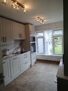 Corridor view of a White Grey shaker kitchen in Swords, Dublin, showing the main run, appliance tower and garden window