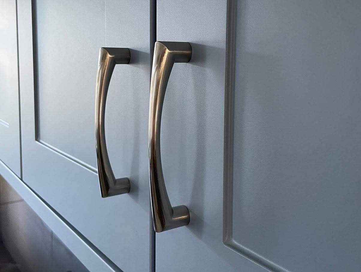 Close-up of two silver Pisa D handles on Denim blue-grey matt shaker cupboard doors