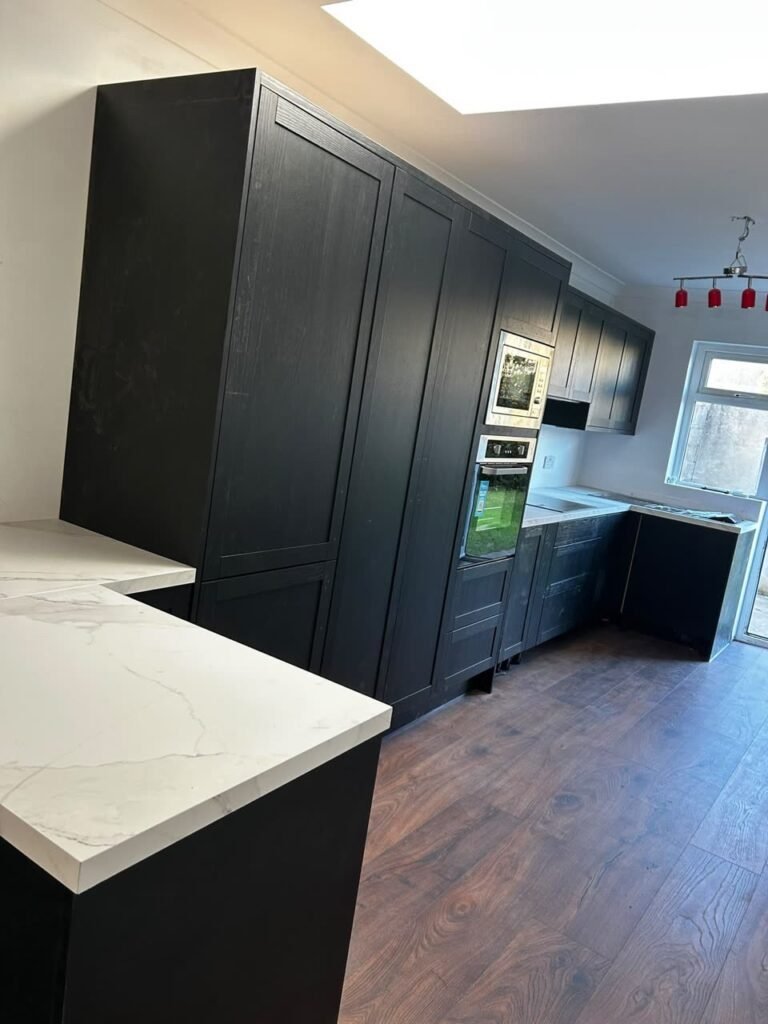 Run of full-height graphite woodgrain shaker cupboards with a built-in microwave stacked above a built-in oven