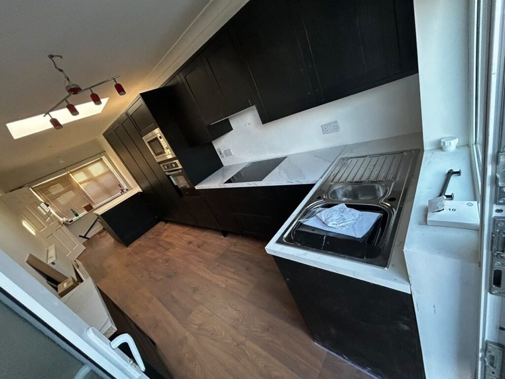 Graphite shaker U-shaped kitchen in Dundrum with a black hob, white marble-effect quartz and a 1.5 bowl stainless steel sink by the window