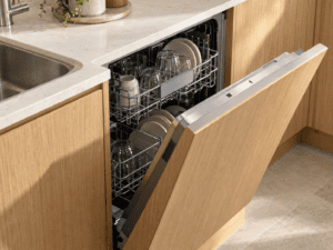 Open integrated dishwasher with a matching oak cabinet front fitted beside the sink in a modern Irish kitchen.