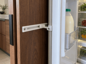 Close-up of a sliding door fitting connecting a walnut cabinet panel to an integrated fridge-freezer.