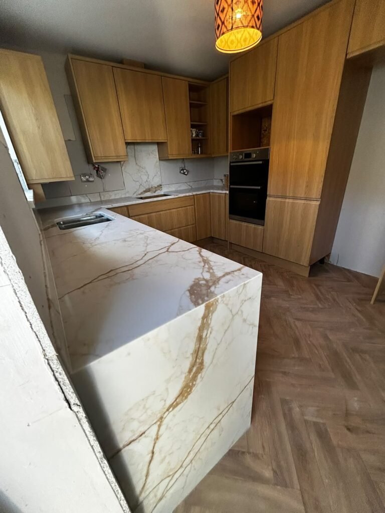 Sink run, open shelves and double oven Oak slab kitchen with a stainless steel double bowl sink in a quartz worktop, open corner shelves and a built-in double oven