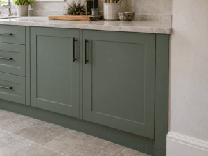 Sage green Shaker kitchen cabinets with a fitted filler panel neatly closing the gap beside the wall.